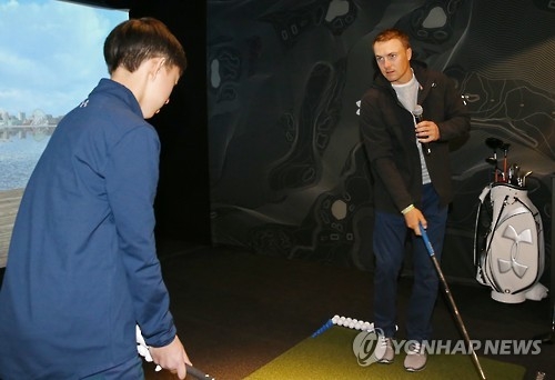 Jordan Spieth (R), the world No. 5 in men's golf, works with a South Korean junior golfer during a clinic at the Under Armour store in Seoul on Jan. 19, 2017. (Yonhap)