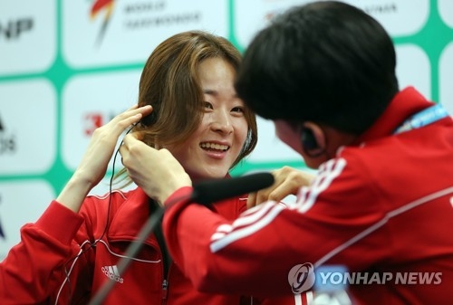 South Korean taekwondo practitioner Oh Hye-ri (L) puts on an earpiece with some help from fellow athlete Lee Dae-hoon before a press conference at the World Taekwondo Federation (WTF) World Taekwondo Championships at T1 Arena in Muju, North Jeolla Province, on June 24, 2017. (Yonhap)