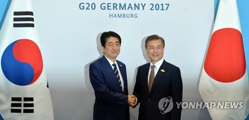 South Korean President Moon Jae-in (R) and Japanese Prime Minister Shinzo Abe shakes hands before the start of their bilateral summit, held on the sidelines of the G20 summit in Hamburg, Germany on July 7, 2017. (Yonhap)