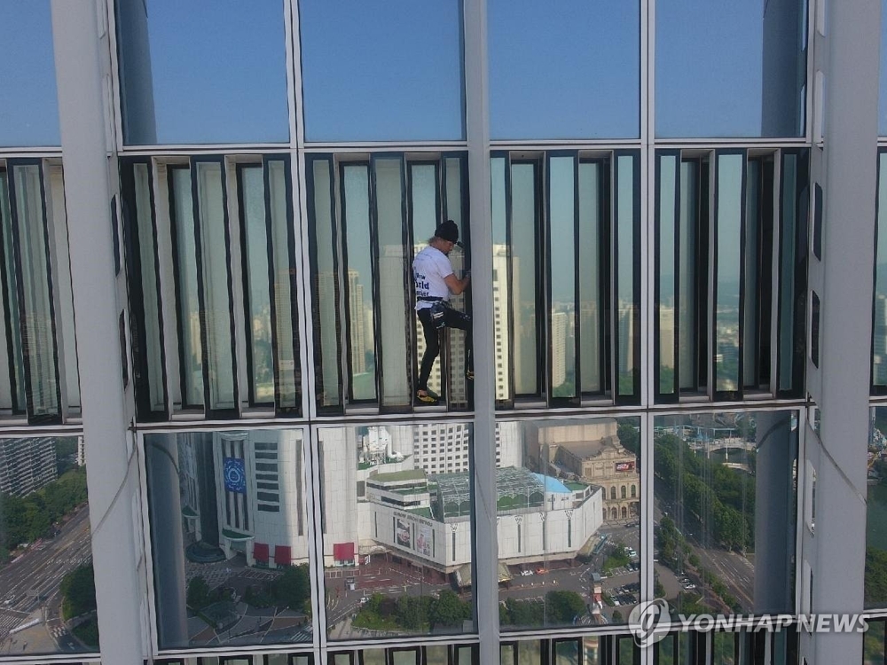 In this photo provided by South Korea's 119 special rescue team, world-renowned French climber Alain Robert climbs the outer wall of Lotte World Tower in southern Seoul on June 6, 2018. Police arrested him on the rooftop for climbing the building without permission from the building's operator. (Yonhap)