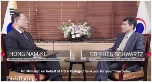 Hong Nam-ki (L), the minister of economy and finance, holds an interview with global credit appraiser Fitch Ratings in this still from a video posted on its website.