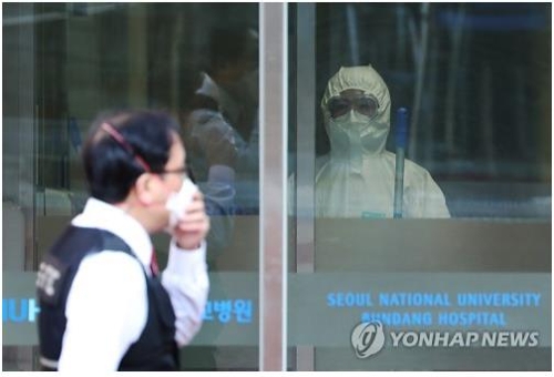 Hospital employees wearing protective gear wait at the entrance to check people for symptoms of the new coronavirus at Seoul National University Bundang Hospital, south of Seoul, on Jan. 29, 2020. (Yonhap)