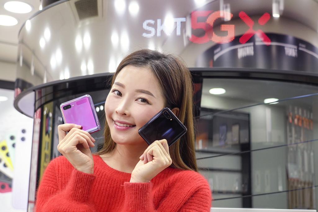 This photo provided by SK Telecom Co. on Feb. 14, 2020, shows a model posing for a photo with Samsung Electronics Co.'s Galaxy Z Flip smartphones. (PHOTO NOT FOR SALE) (Yonhap)