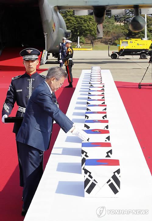 President Moon Jae-in puts war medals on the remains of 64 South Korean soldiers killed in North Korea during the 1950-53 Korean War on Oct. 1, 2018, Armed Forces Day, after they arrived at Seoul Air Base in Seongnam, southeast of Seoul, from Hawaii. The remains were found during a joint excavation project between the United States and North Korea in major Korean War battle zones in the communist state from 1996-2005. (Yonhap)