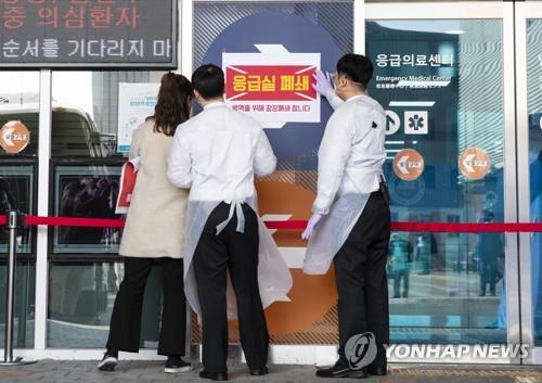 Workers at Hanyang University Hospital in Seoul post a notice saying the emergency center is temporarily closed on Feb. 19, 2020, to prevent the spread of the novel coronavirus. (Yonhap)