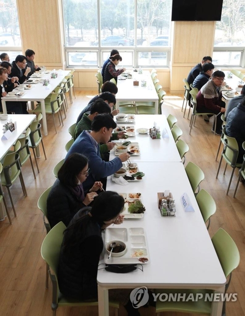 Employees of Suwon Urban Development Corp. eat lunch seated only on one side of the table at the corporation's building in Suwon, just south of Seoul, on March 2, 2020, amid concern over the spread of the new coronavirus. (Yonhal)
