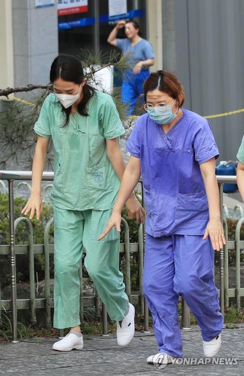 Medical workers walk to a resting place, their bodies soaked with sweat, after working a shift helping people infected with the new coronavirus at a hospital in the southeastern city of Daegu on March 19, 2020. (Yonhap)