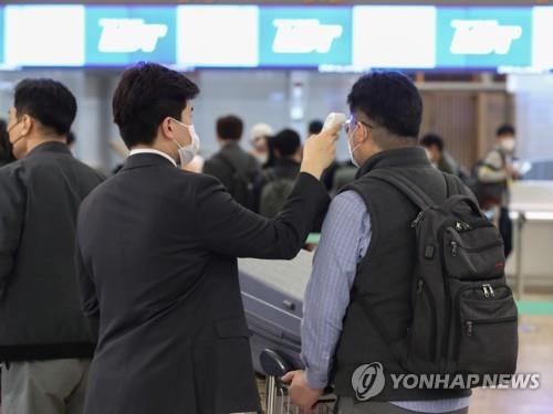 An LG Chem worker (R) undergoes a body temperature check before boarding a special flight to Poland at Incheon International Airport, west of Seoul, on April 17, 2020. (Yonhap)