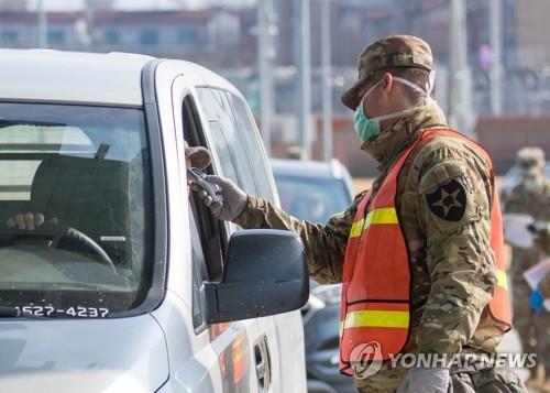 A military guard at U.S. Army Garrison Humphreys in Pyeongtaek, 70 kilometers south of Seoul, checks the temperature of a driver to screen entrants to the compound for the novel coronavirus, on Feb. 28, 2020, in the photo provided by United States Forces Korea. (PHOTO NOT FOR SALE) (Yonhap)