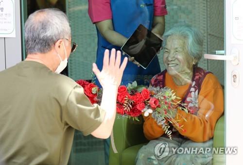 A son waves to his mother from behind a glass panel at a senior care facility in the central city of Daejeon on May 7, 2020, as he meets her without person-to-person contact one day ahead of Parents' Day amid the spread of the new coronavirus. (Yonhap)
