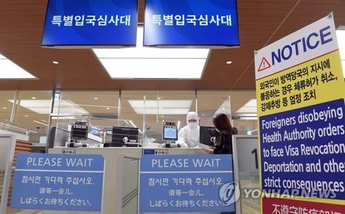 This file photo taken April 8, 2020, shows a customs official explaining self-isolation rules to a foreign visitor. (Yonhap)