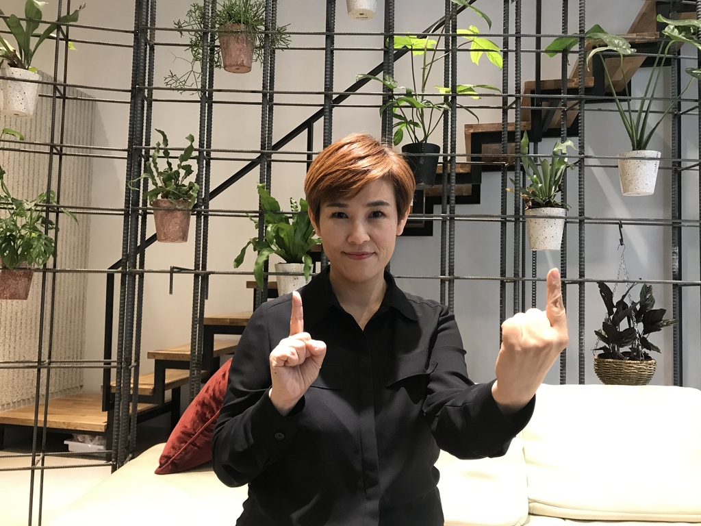 Sign language interpreter Koh Koung-hee signs the term "social distancing" during a recent interview with Yonhap News Agency in Seoul. Koh, who showed up in an olive-colored shirt, changed to black attire to better demonstrate her signing. (Yonhap)