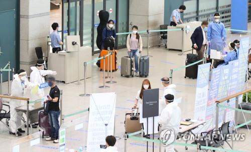 This photo taken on July 28, 2020, shows health workers guiding arrivals at Incheon International Airport in Incheon. (Yonhap)