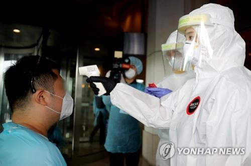 In this photo, taken by the Joint Press Corps on Aug. 5, 2020, a health worker checks the body temperature of an arrival at a shelter in Incheon. (Yonhap)