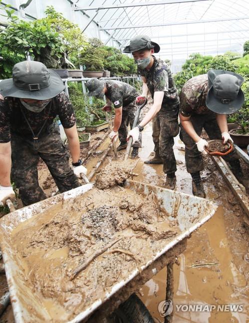 Soldiers remove mud from a greenhouse as they carry out restoration work in the city of Anseong, south of Seoul, following heavy rains in the region, on Aug. 5, 2020. (Yonhap)