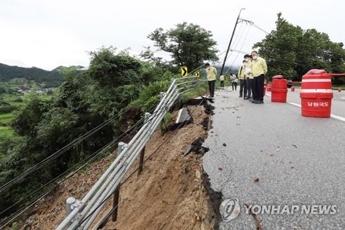 Officials inspect a road partially swept away by torrential rain in Namwon, North Jeolla Province, on Aug. 10, 2020, in this photo provided by the Ministry of Land, Infrastructure and Transport. (PHOTO NOT FOR SALE) (Yonhap)