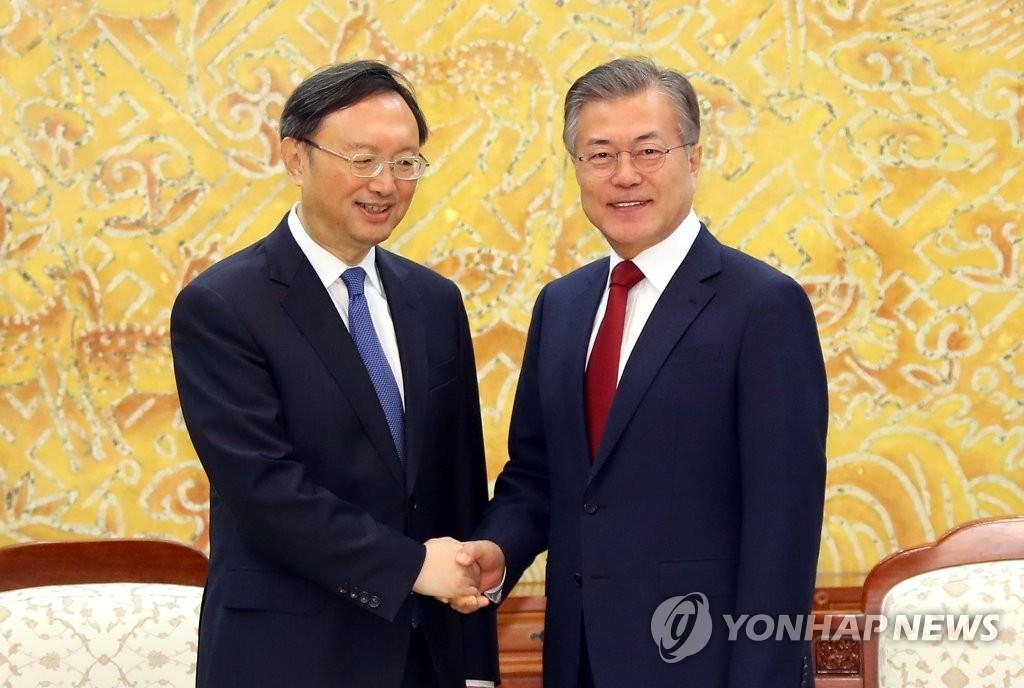 This file photo shows South Korean President Moon Jae-in (R) shaking hands with Yang Jiechi, a member of the Political Bureau of the Communist Party of China (CPC) Central Committee, at Cheong Wa Dae in Seoul on March 30, 2018. (Yonhap)