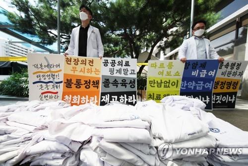 Medical workers stage a rally at Ajou University Medical Center in Suwon, south of Seoul, on Aug. 26, 2020, with their folded gowns piled up, as tens of thousands of doctors launched a full-scale strike nationwide in protest of the government's move to increase the number of medical students. (Yonhap)