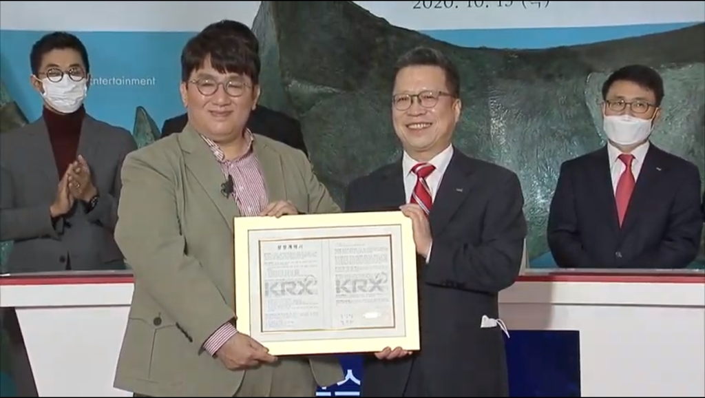 This photo, captured from Big Hit Entertainment's live video channel, shows the company's head Bang Si-hyuk (L) and Korea Exchange (KRX) chief Jung Ji-won posting for photos at the K-pop entertainment giant's listing ceremony held at KRX's Seoul headquarters on Oct. 15, 2020. (Yonhap)