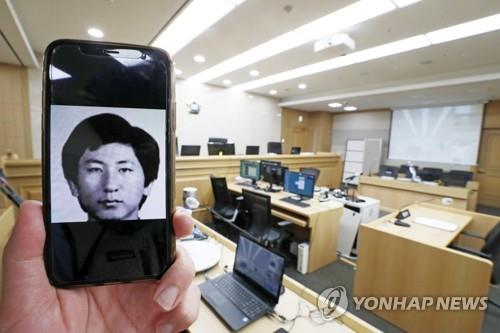This photo shows a courtroom at Suwon District Court in Suwon, south of Seoul, where on Nov. 2, 2020, Lee Chun-jae (shown in the image on the mobile phone), the suspect in one of the nation's most notorious serial killings, testified about his rape and murder of a 13-year-old girl in 1988 during the retrial of a man who was convicted and served 20 years in prison in the case. (Yonhap)