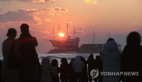 This undated file photo shows people watching the sunrise on Jeongdongjin Beach in Gangneung, Gangwon Province. (Yonhap)