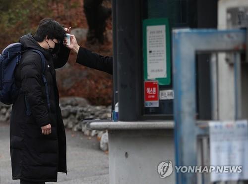 A school official checks the temperature of a student in a high school in Seoul on March 2, 2021. (Yonhap)