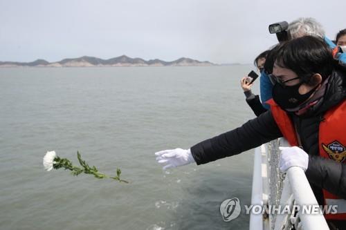 A victim's family member throws a flower into the waters near where the Sewol ferry sank off the coast of Jindo Island in South Korea on April 16, 2021. (Yonhap)