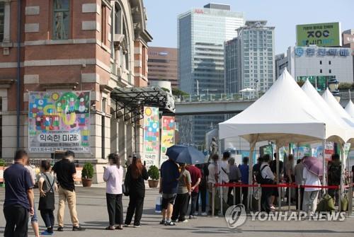 People stand in line to take coronavirus tests at a screening clinic in front of Seoul Station on July 23, 2021. South Korea's daily new coronavirus cases dropped from the previous day's all-time high, but authorities extended the toughest virus curbs in the wider Seoul area to curb a further rise in new infections. (Yonhap)