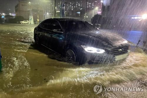 A car drives on a flooded road in the southwestern city of Yeosu, South Jeolla Province, on Aug. 23, 2021, following heavy rain caused by Typhoon Omais. (Yonhap)