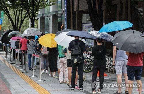People holding umbrellas stand in line to take coronavirus tests at a screening clinic in Seoul on Sept. 7, 2021. (Yonhap)