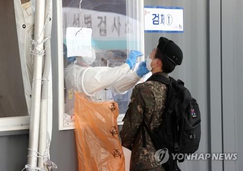 This file photo taken on May 24, 2021, shows a service member undergoing a COVID-19 test at a makeshift testing station in front of Seoul Station in central Seoul. (Yonhap)