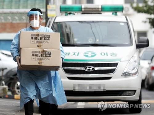 A health worker carries "self-treatment kits" for the coronavirus in Incheon, 40 kilometers west of Seoul, on Oct. 19, 2021. They will be used by people infected with the coronavirus who have no symptoms or mild ones and are taking care of themselves at home. (Yonhap)