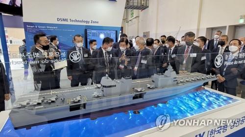 Visitors look at a model of a Korean-style light aircraft carrier of Daewoo Shipbuilding & Marine Engineering Co. during the International Marine, Shipbuilding, Offshore, Oil and Gas Exhibition 2021 at the BEXCO convention center in the southeastern port city of Busan on Oct. 19, 2021. The exhibition, which opened the same day and runs through Oct. 22, brings together representatives of 700 companies from 30 countries. (Yonhap)