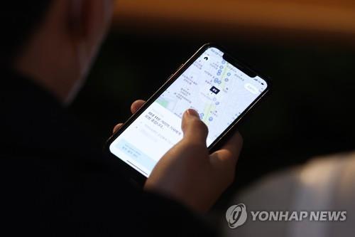 A person tries to call a taxi on a smartphone application in the busy district of Gangnam in southern Seoul on April 19, 2022. (Yonhap)
