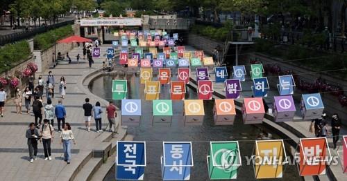People take a leisurely walk along Cheonggye Stream in downtown Seoul on May 22, 2022. (Yohnap)