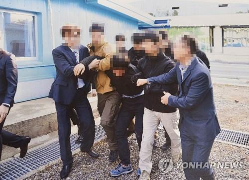 This photo, provided by the Ministry of Unification on July 12, 2022, shows a North Korean fishermen who was captured near the eastern inter-Korean sea border, resisting as South Korean authorities repatriate him back to the North in the inter-Korean truce village of Panmunjom in November 2019. (PHOTO NOT FOR SALE) (Yonhap)