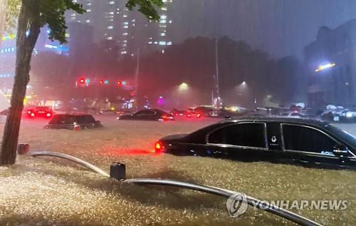 This photo provided by a news reader shows cars submerged in a flooded road near Seoul's Daechi subway station on Aug. 8, 2022. (PHOTO NOT FOR SALE) (Yonhap)