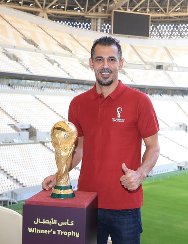 Former Iraq captain Younis Mahmoud poses with the 2022 FIFA World Cup Winner's Trophy after being named an ambassador for the tournament in Qatar, in this photo provided by Qatar's World Cup organizing committee on Sept. 13, 2022. (PHOTO NOT FOR SALE) (Yonhap)