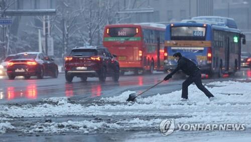 A worker removes snow on a sidewalk in Seoul in this undated file photo. (Yonhap)