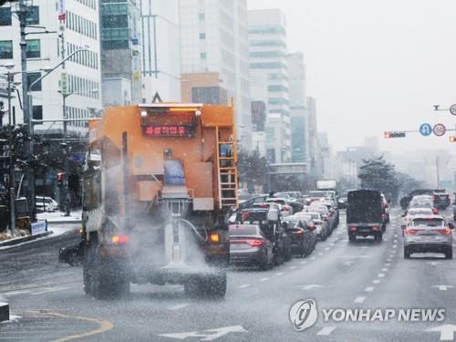 A snow-clearing vehicle runs on a snow-covered road in Suwon, just south of Seoul, on Jan. 26, 2023. (Yonhap)
