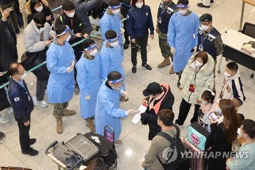 In this file photo taken Jan. 2, 2023, quarantine officials in blue gowns guide travelers arriving from China to undergo a PCR test at Incheon International Airport, west of Seoul. (Yonhap)