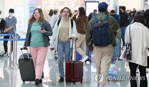 Travelers walk mask-free at Incheon International Airport, west of Seoul, on March 20, 2023, the first day that the indoor mask mandate was lifted on public transportation. (Yonhap)