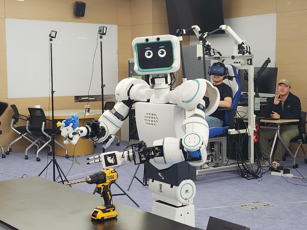 Avatar (L), a robot developed by professor Bae Joon-bum and his team, and its operator (2nd from R) pose for the camera at a lab of the Ulsan National Institute of Science and Technology on April 28, 2023. (Yonhap)