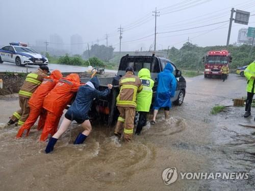 Firefighters move a truck out of a submerged area in the southeastern port city of Busan, in this photo provided by fire authorities on July 16, 2023. (PHOTO NOT FOR SALE) (Yonhap)
