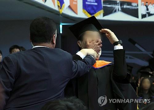 A presidential security agent (L) covers the mouth of a student protesting at President Yoon Suk Yeol (not pictured) during the commencement ceremony of the Korea Advanced Institute of Science and Technology in Daejeon, 139 kilometers south of Seoul, on Feb. 16, 2024. (Pool photo) (Yonhap)