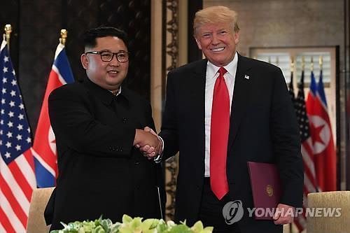 Esta fotografía de la AFP muestra al presidente de Estados Unidos, Donald Trump (derecha), estrechando la mano del líder norcoreano Kim Jong-un después de firmar una declaración conjunta en el Hotel Capella en la isla Sentosa en Singapur el 12 de junio de 2018. (Yonhap)