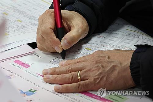 En esta foto de archivo, una persona mayor que busca empleo llena un formulario de solicitud en una feria de empleo en Seúl el 13 de diciembre de 2023. (Yonhap)