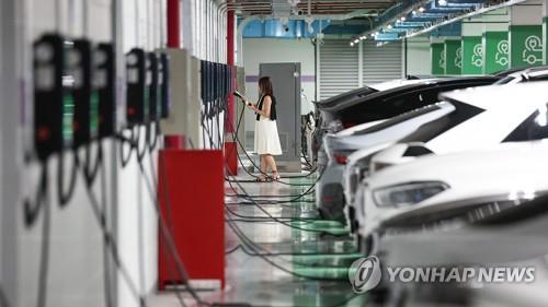 This photo taken Aug. 16, 2023, shows a woman charging her electric vehicle at a charging station in Seoul. (Yonhap)