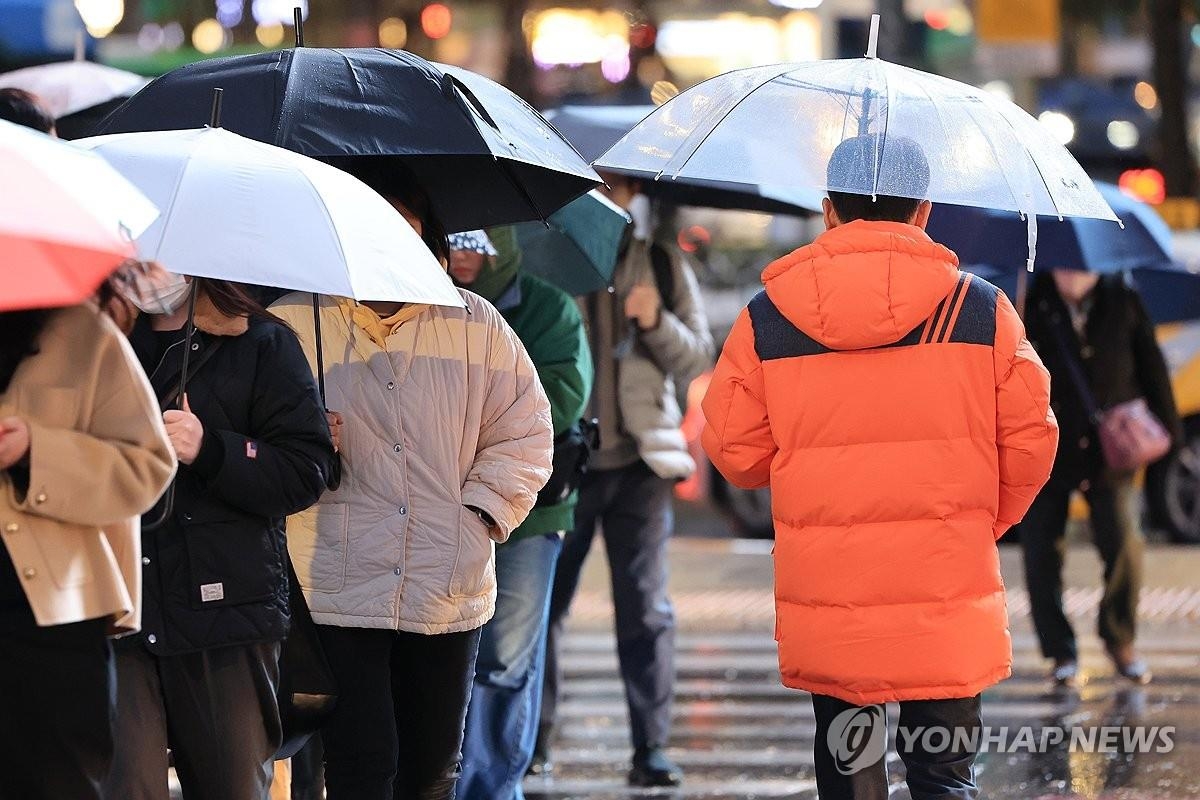 Esta foto tomada el 26 de noviembre de 2024 muestra a personas con abrigos de invierno caminando bajo la lluvia en el centro de Seúl. (Yonhap)