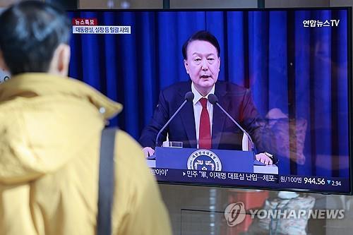 A person watches news on the short-lived martial law declaration in South Korea at Seoul Station in the capital on Dec. 4, 2024. (Yonhap)